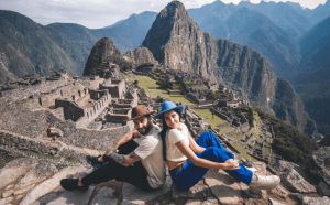 couple sitting back to back in front of Machu Picchu
