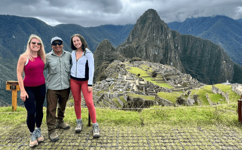 viajeros con guia frente a las ruinas de machu picchu